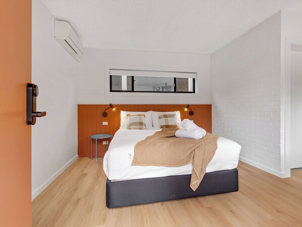 A modern bedroom with a bed, bedside tables, and a window.