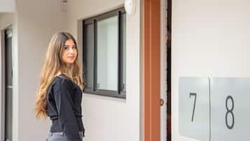 A person standing in a hallway with a door marked with the numbers 78.