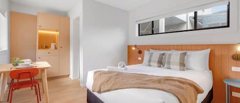 Una habitación de hotel moderna con cama, escritorio y silla.
