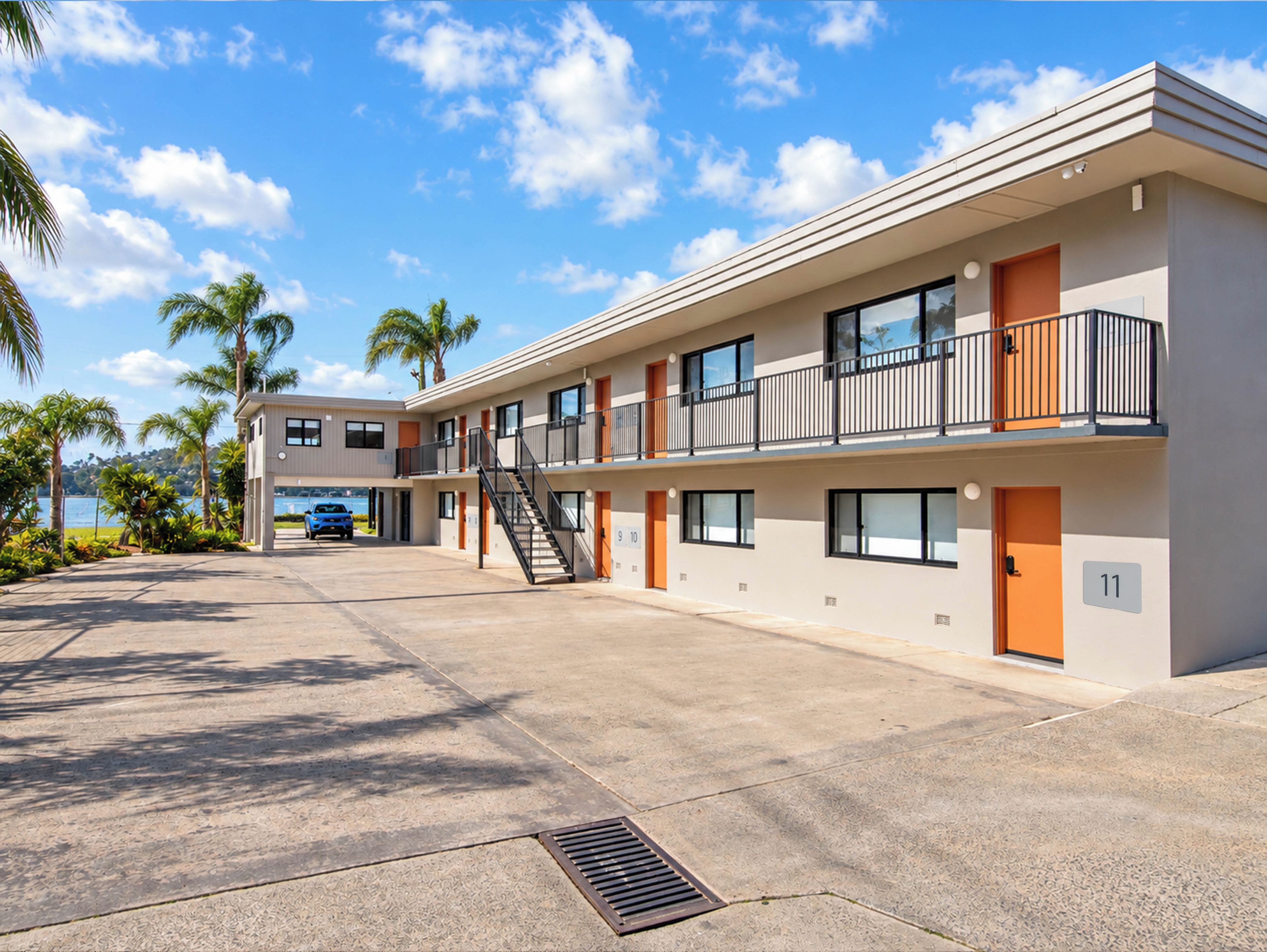 A multi-story motel with a parking area, a staircase, and a view of the ocean.
