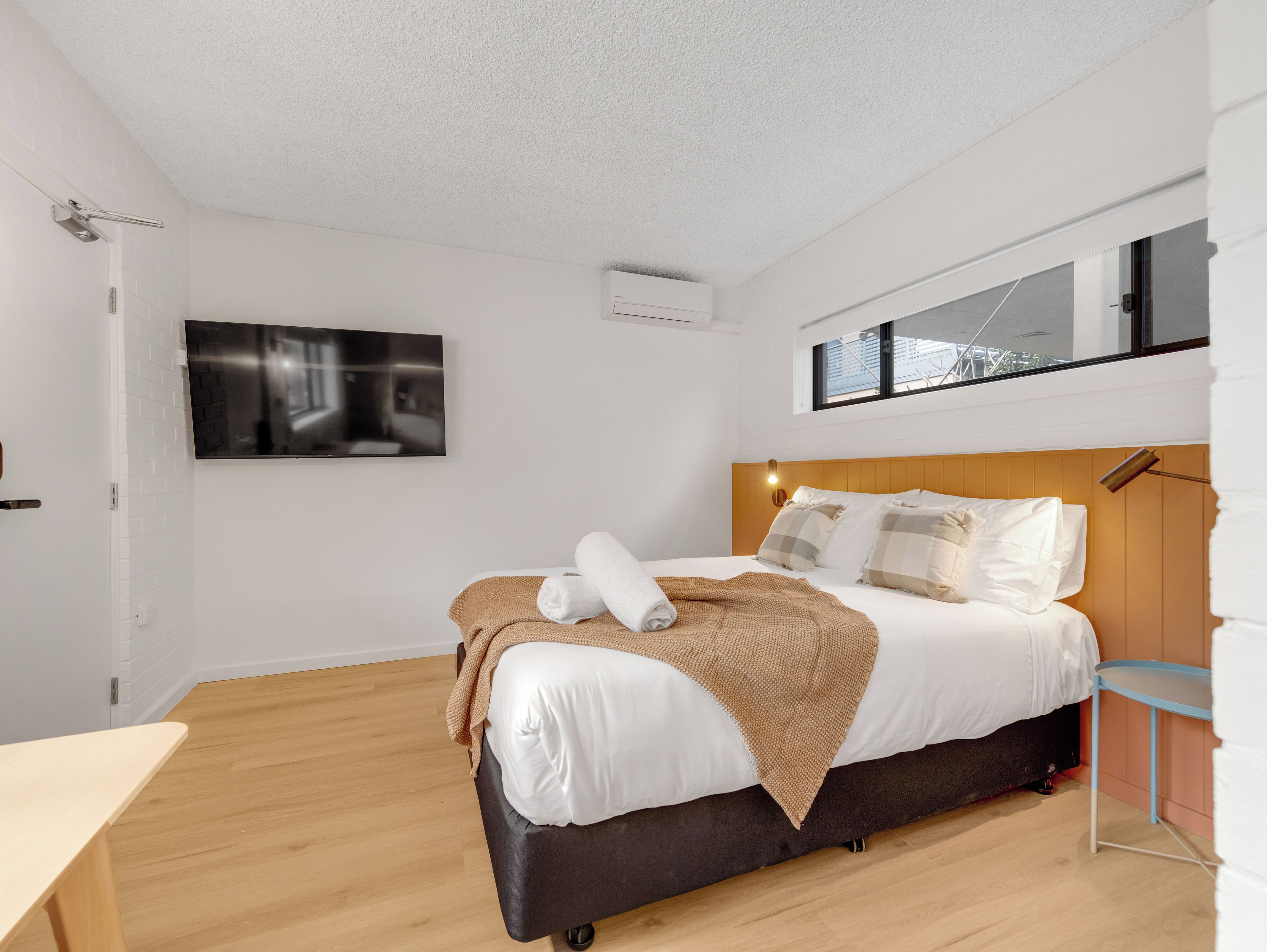 A modern bedroom with a bed, a flat-screen TV, and a window.