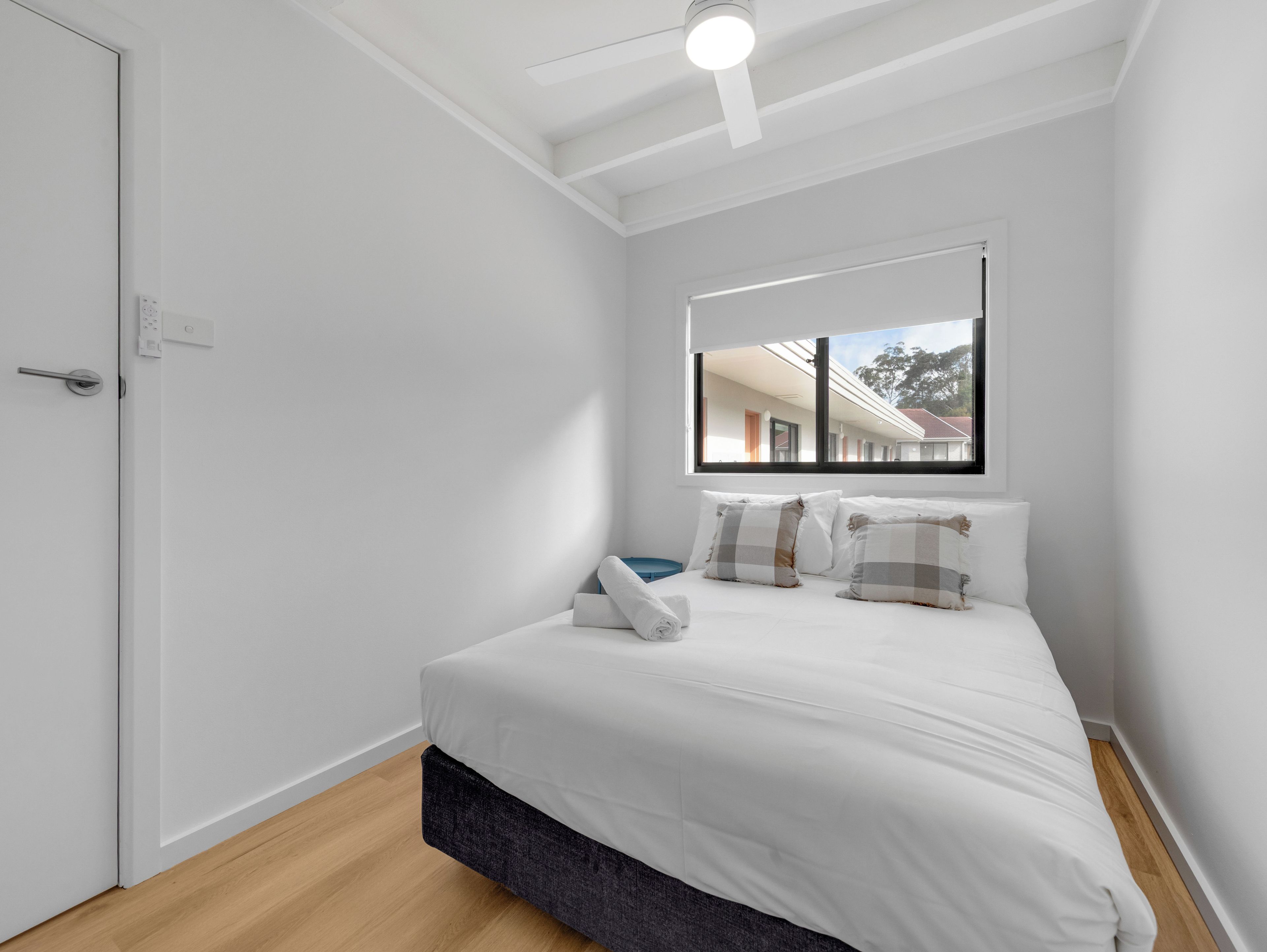 A bedroom with a bed, a window, and a door.