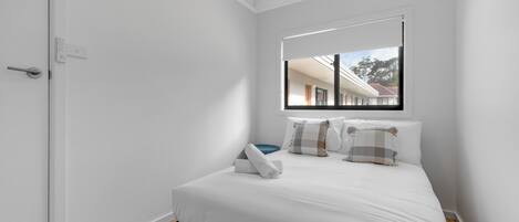 A bedroom with a bed, a window, and a door.