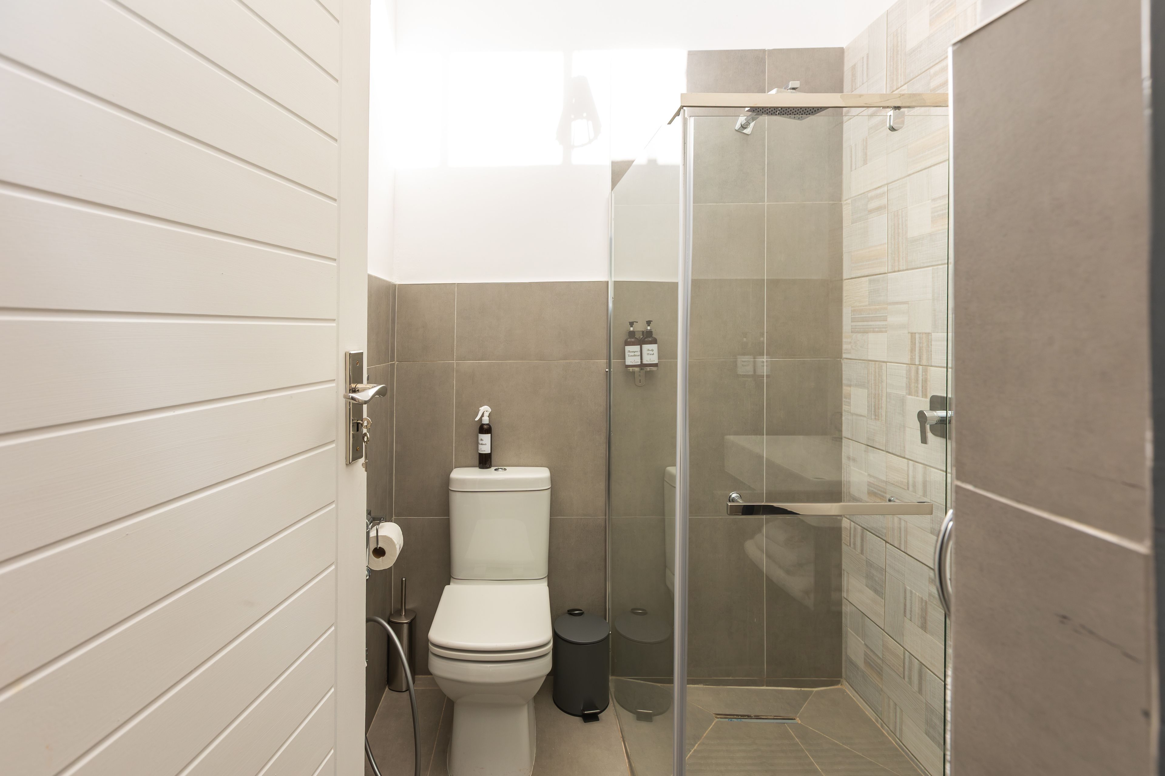 A bathroom with a toilet, a glass-enclosed shower, and a toilet paper holder.