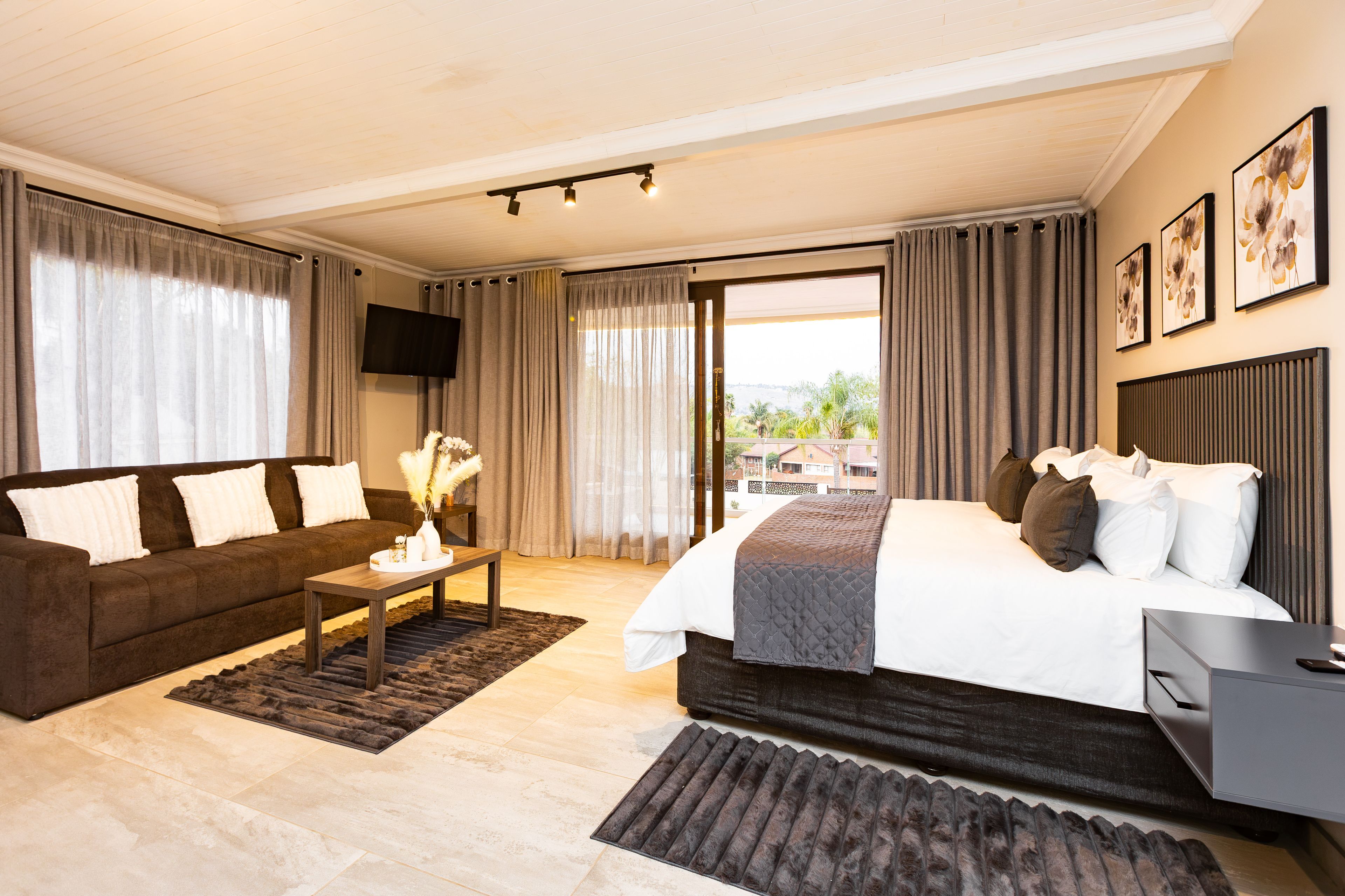 Une chambre d’hôtel avec un lit, un canapé, une télévision et une vue sur l’extérieur.
