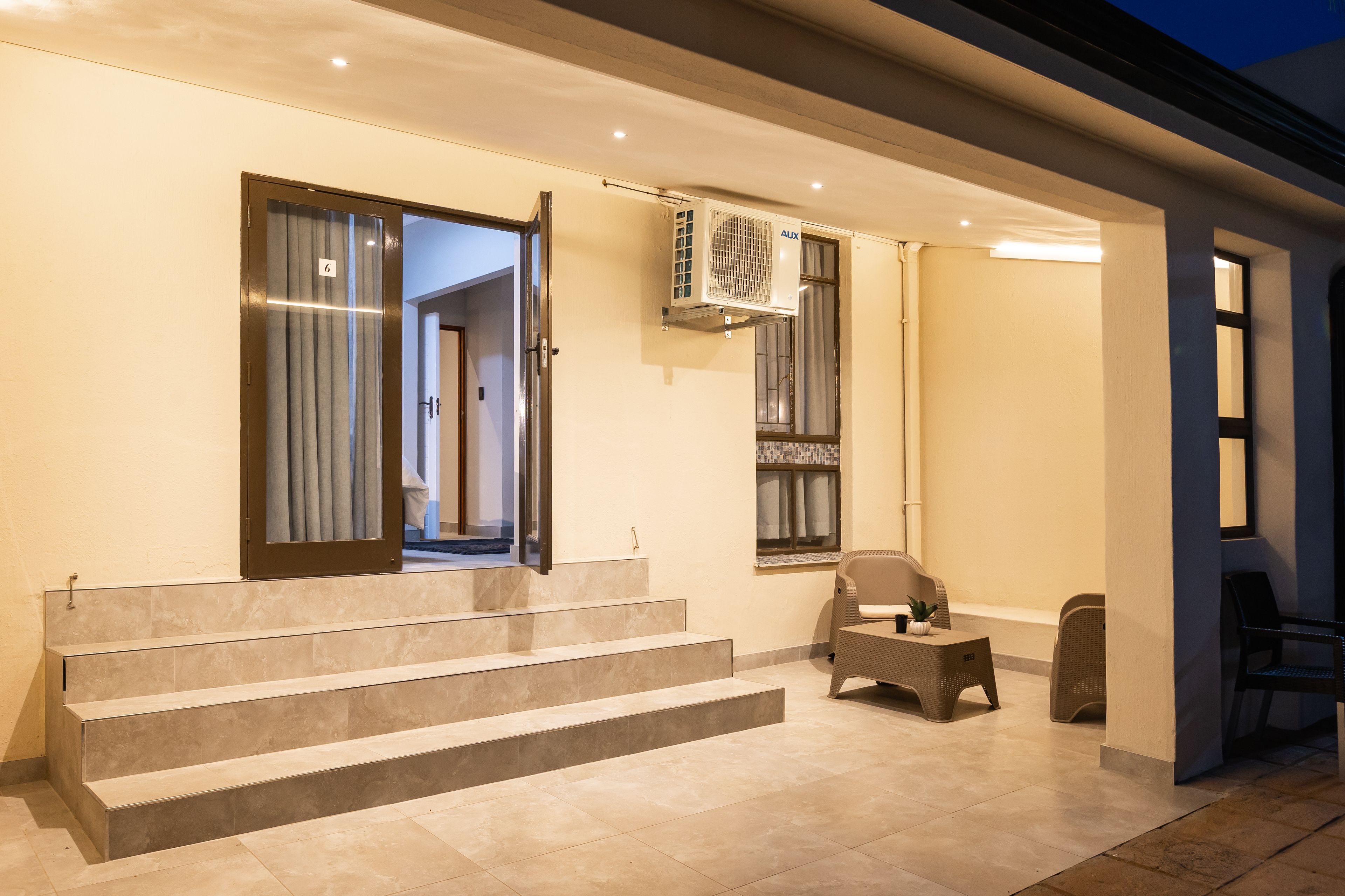 A hotel entrance with a set of stairs leading to a room, a window with curtains, and a wall-mounted air conditioning unit.