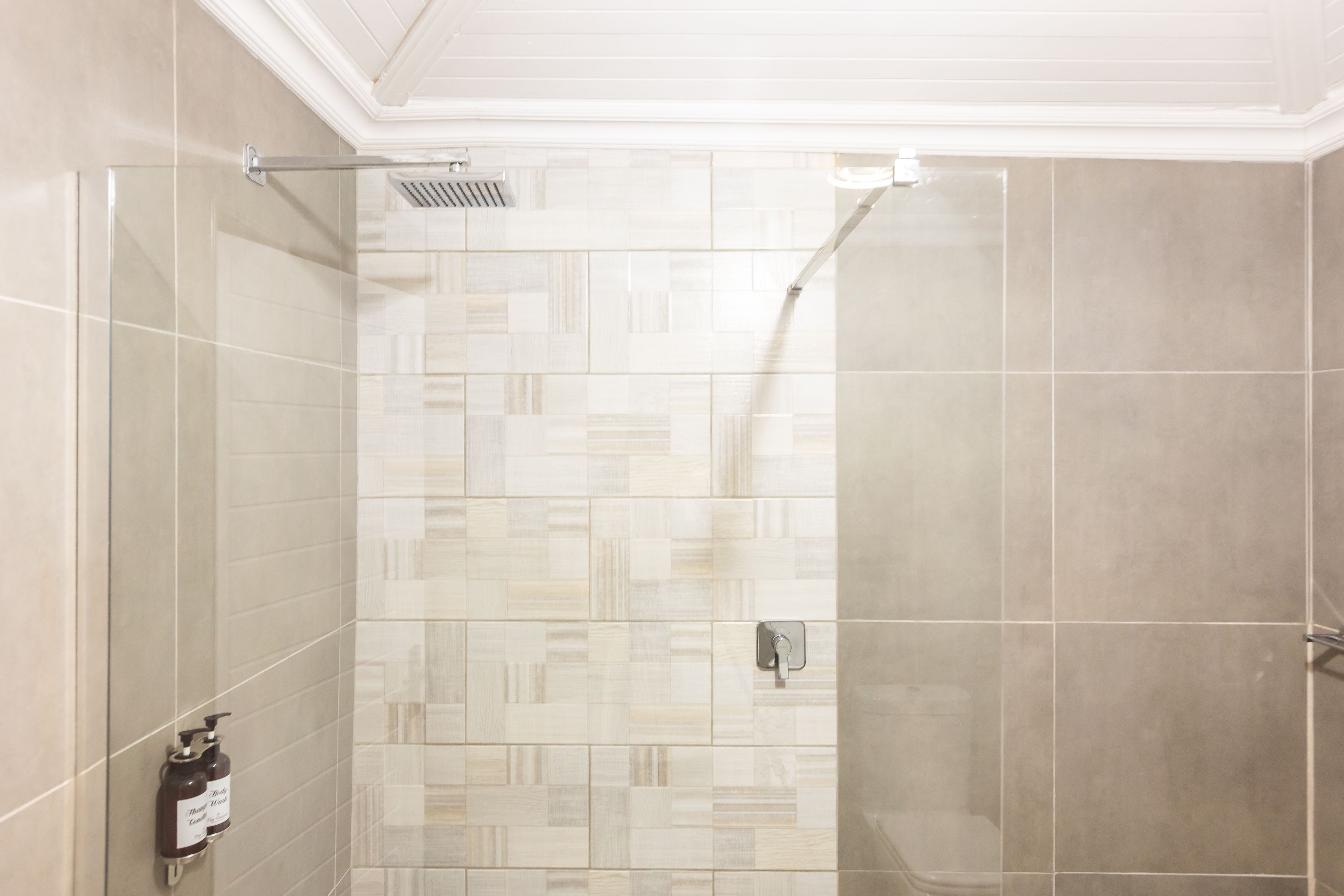 Ducha con pared de azulejos y dispensador de jabón.