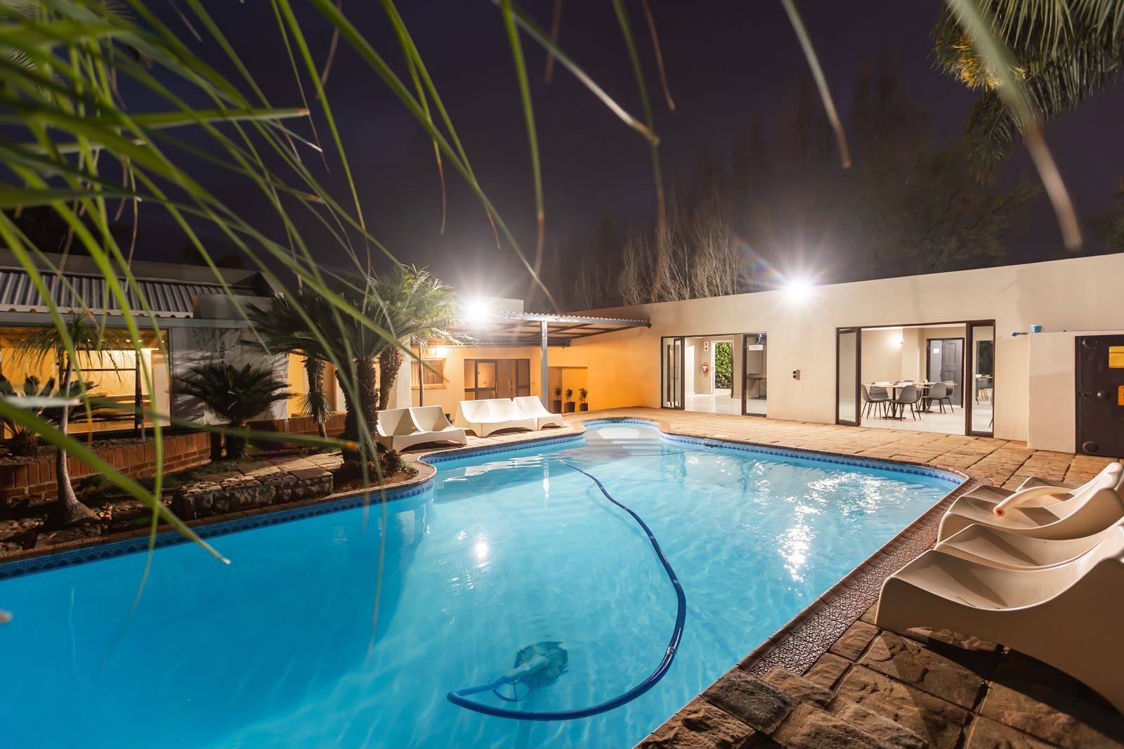 Una piscina al aire libre con sillas de descanso y un patio cubierto.
