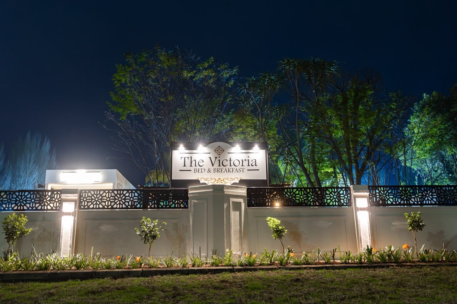 A sign for 'The Victoria Bed & Breakfast' with a decorative fence and plants in front.