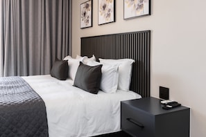 A modern hotel room with a bed, a nightstand, and a wall-mounted power outlet. - The Victoria Bed & Breakfast (Newcastle)