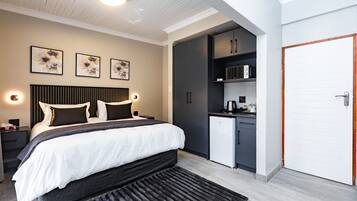 Ein modernes Schlafzimmer mit einem Bett, Nachttischen, einem Schreibtisch, einem Kleiderschrank und einer Küchenzeile.