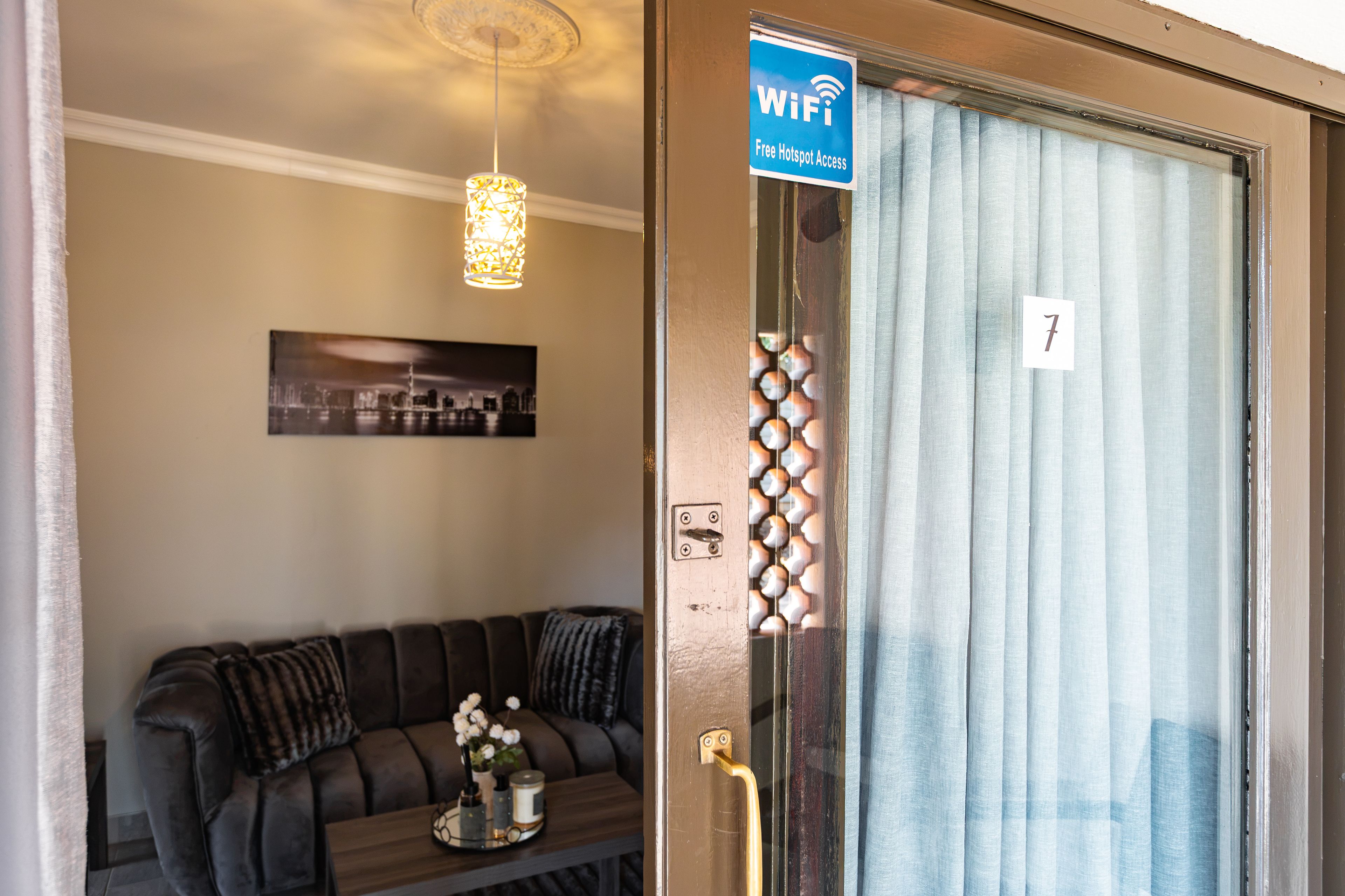 Una habitación con un sofá, una puerta con un número y un letrero que indica acceso a internet WiFi gratuito.