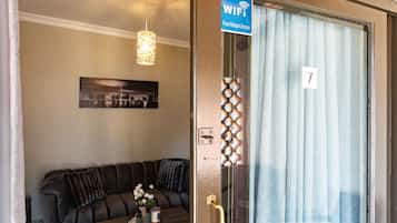 Una habitación con un sofá, una puerta con un número y un letrero que indica acceso a internet WiFi gratuito.