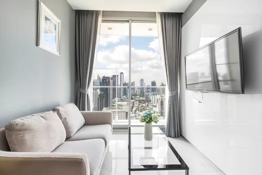Ein modernes Wohnzimmer mit einer Couch, einem Couchtisch, einem Fernseher und einem großen Fenster mit Blick auf die Stadt.