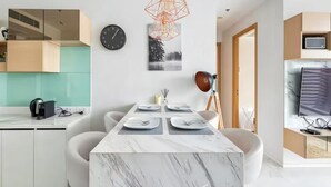 A modern kitchen with a marble countertop, a dining table set for four, and a pendant light. - Hyde 11 Sukhumvit Bangkok (Krung Thep Maha Nakhon)