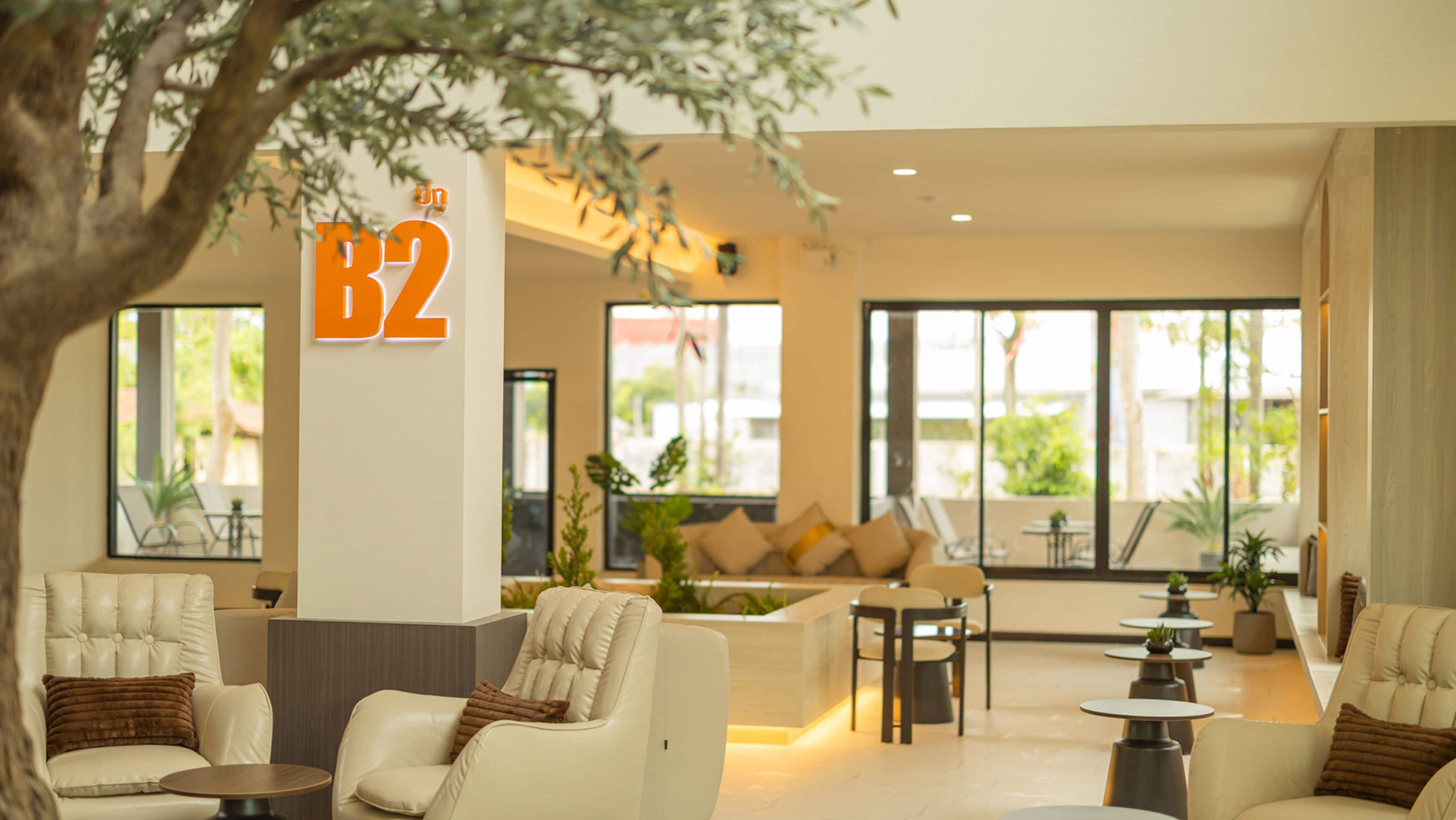 A modern hotel lobby with a seating area, a reception desk, and large windows offering a view of the outdoors.