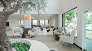 A modern interior with seating areas, a reception desk, and large windows offering views of the outdoors.