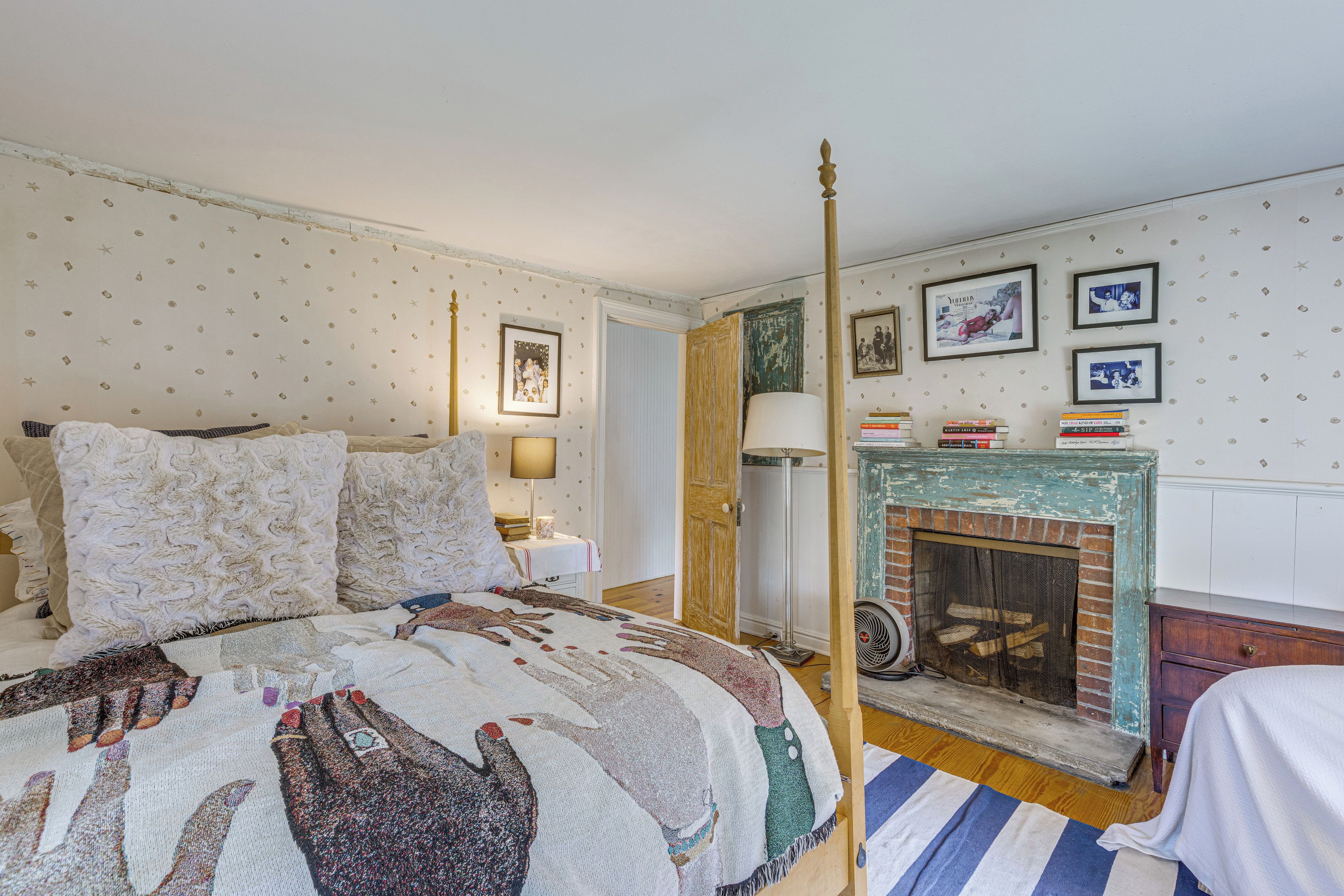 A bedroom with a four-poster bed, a fireplace, and a bookshelf.