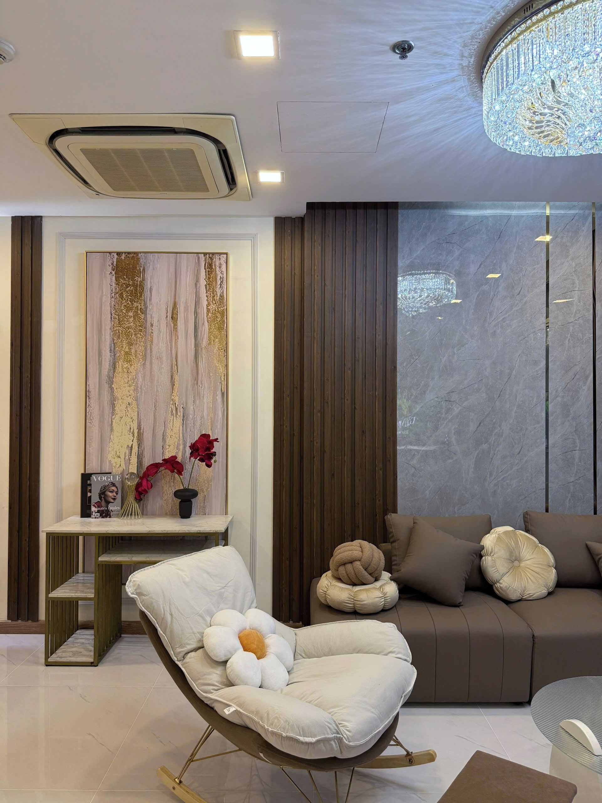A modern living room with a sofa, a chair, a decorative wall, and a chandelier.