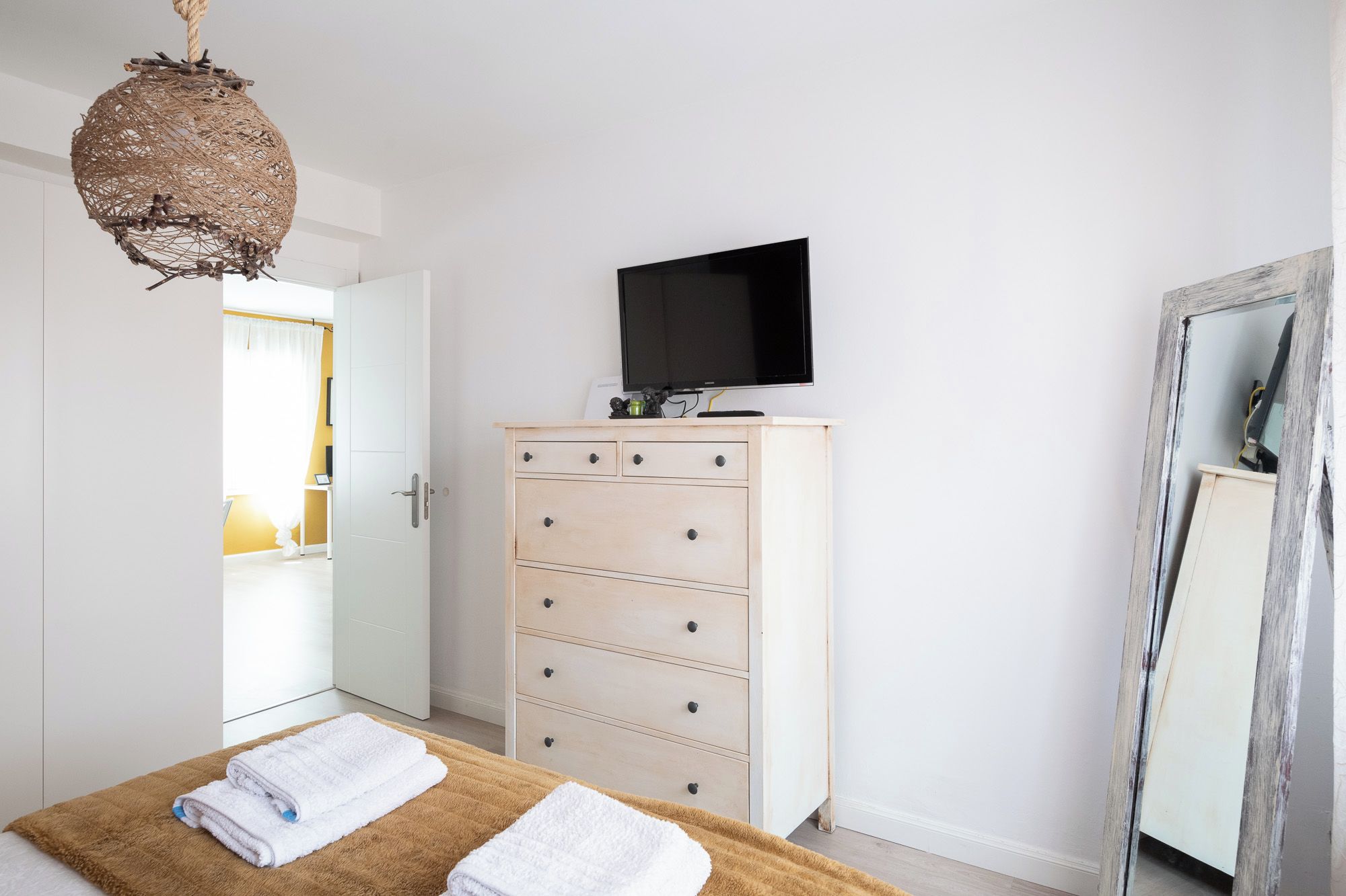 Un dormitorio con cama, cómoda, televisor y espejo.