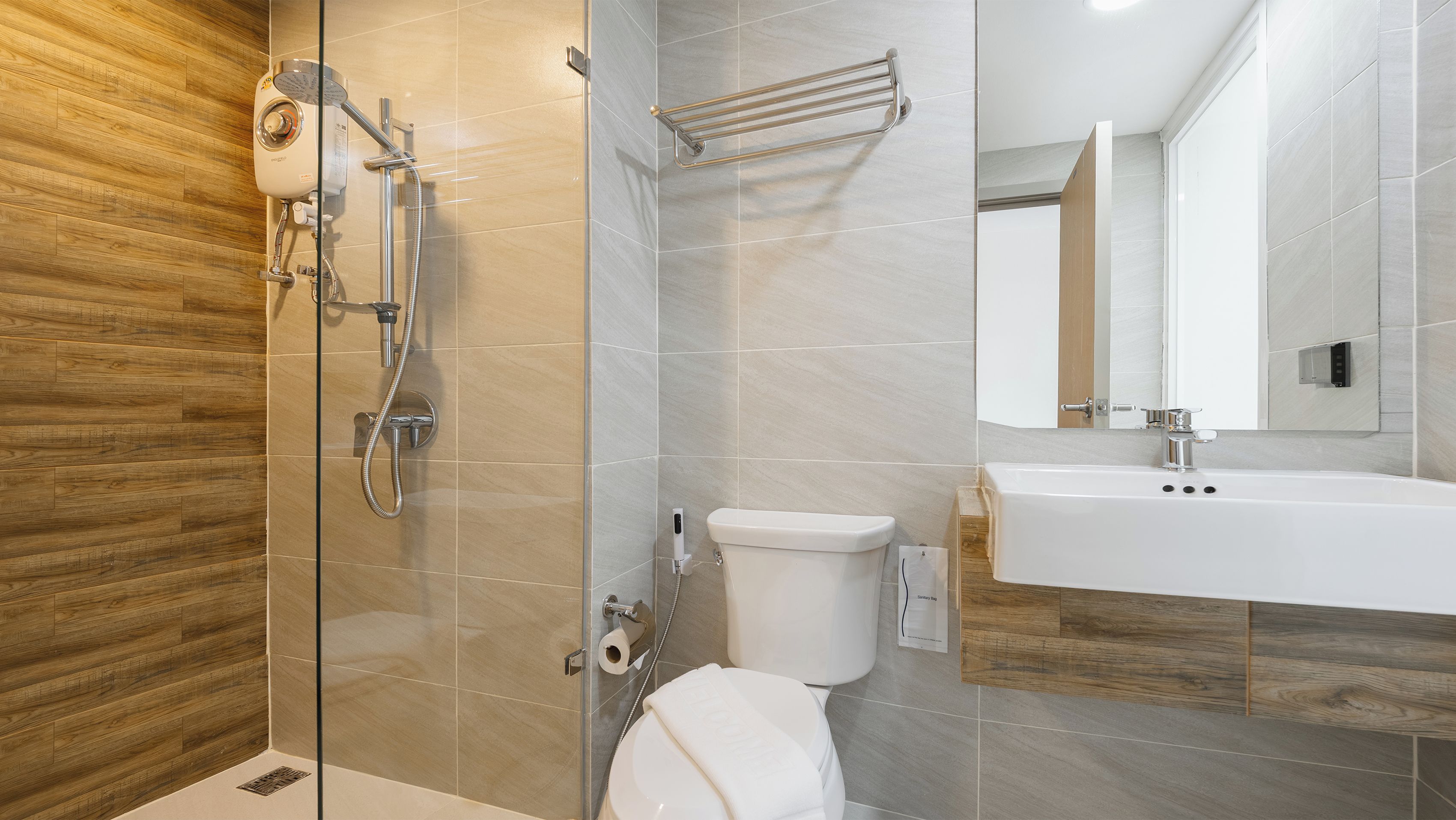 A modern bathroom with a glass-enclosed shower, a toilet, and a sink with a mirror above.