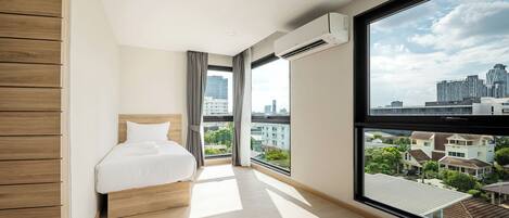 Una habitación de hotel moderna con un ventanal grande, una cama y un equipo de aire acondicionado.