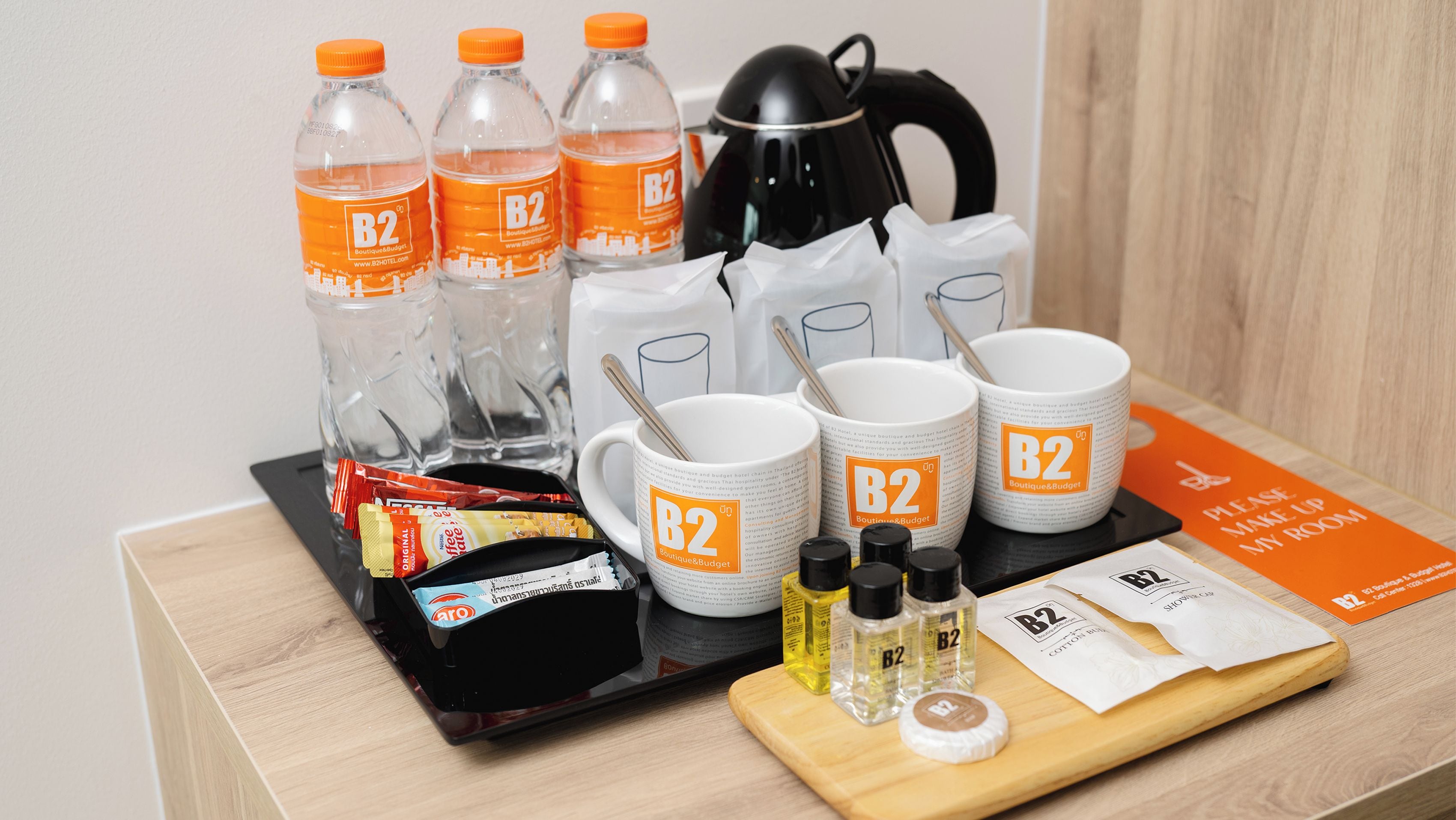 A hotel room setup with toiletries, a kettle, and a tray with various items.