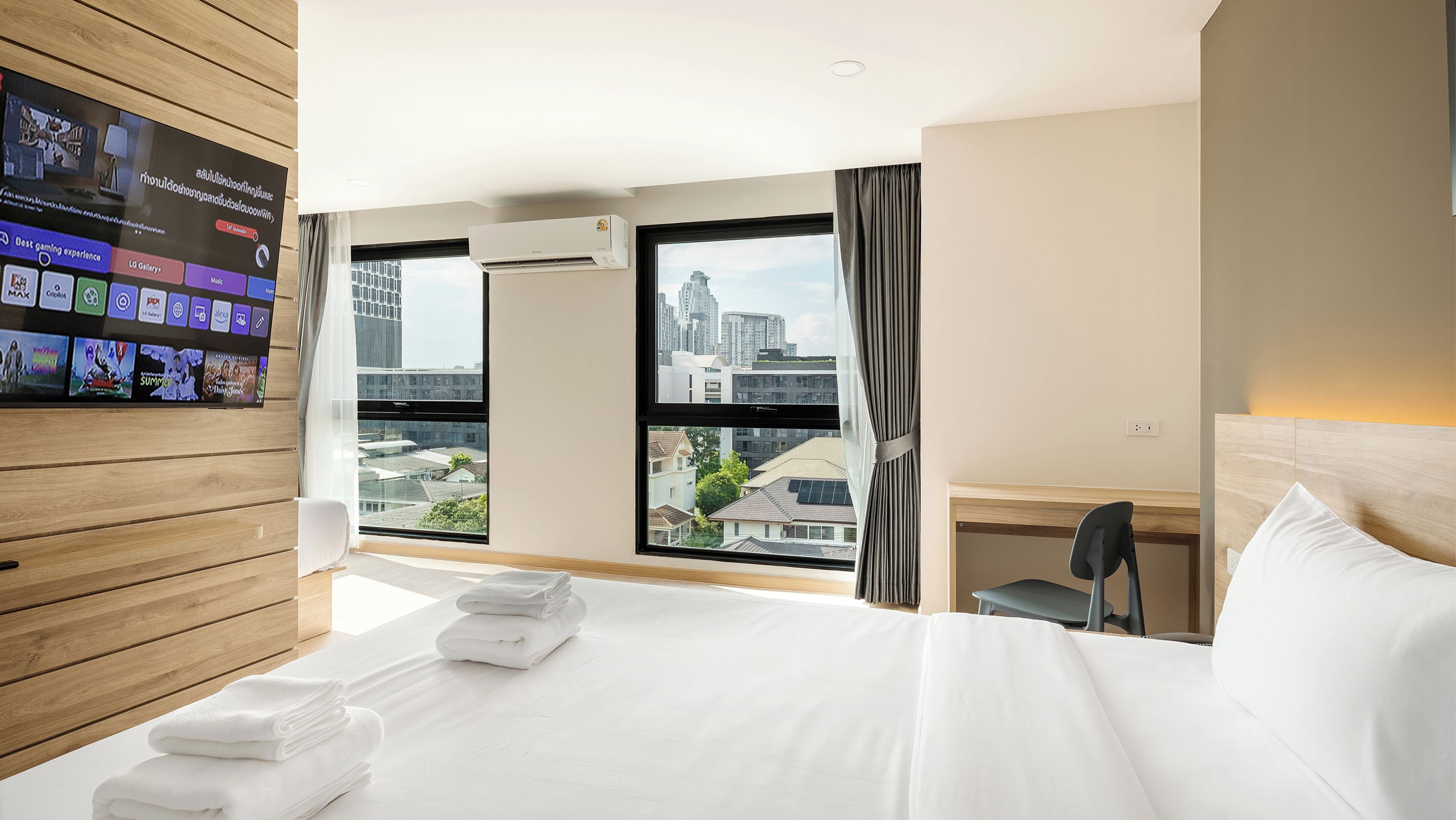 Een hotelkamer met een groot bed, een bureau, een aan de muur bevestigde televisie en uitzicht op de stadsplattegrond.