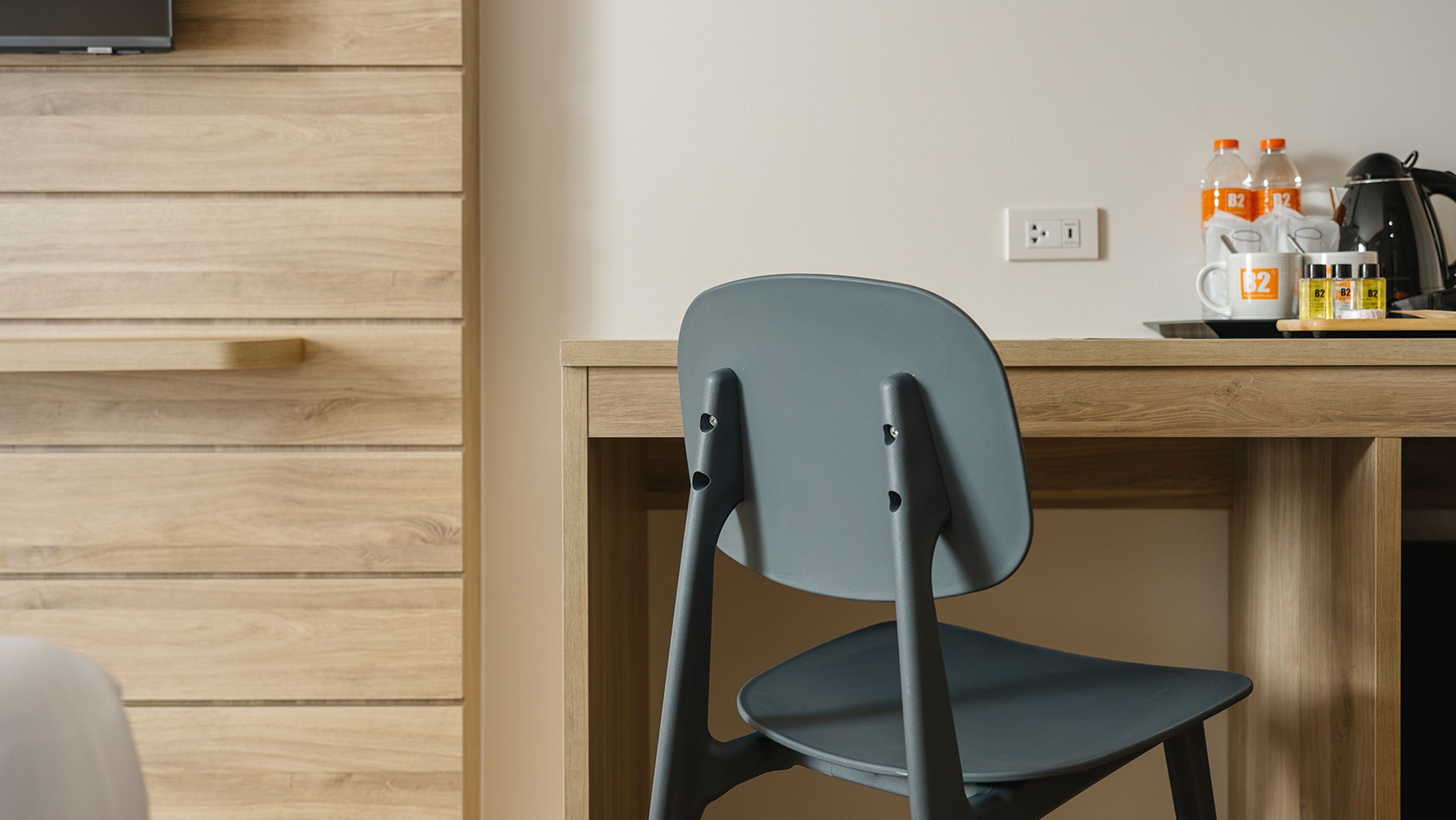 A modern room with a wooden wall, a desk with a chair, and a television mounted above the wall.
