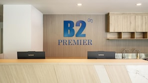 Un comptoir d’accueil avec un panneau arrière en bois, deux ordinateurs portables Lenovo et un lavabo doté de robinets modernes.
