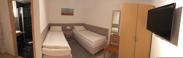 A hotel room with a shower, two beds, a TV, and a painting on the wall.