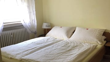 Ein Einzelbett mit Holzrahmen, ein Nachttisch mit Lampe und eine Heizung.