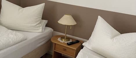 A hotel room with two beds, a nightstand with a lamp, and a painting on the wall.