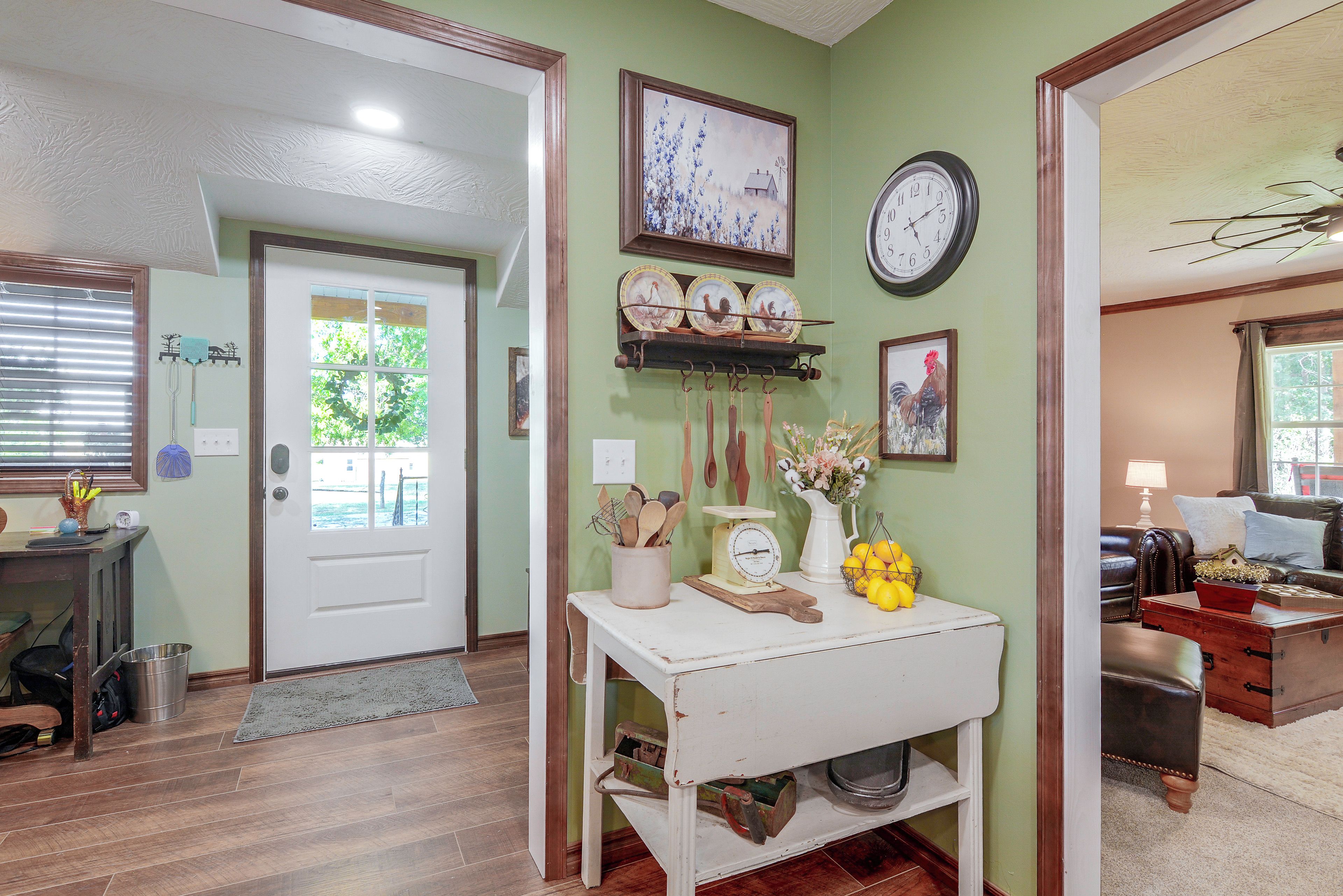 A hallway with a white door, a clock, and a shelf with kitchen utensils.