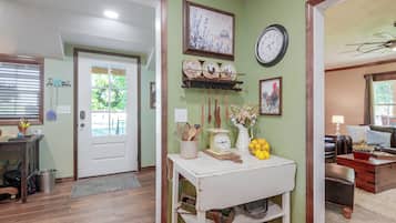 A hallway with a white door, a clock, and a shelf with kitchen utensils.