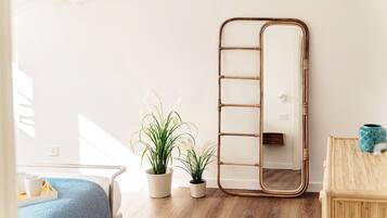 A room with a bed, a mirror, and two potted plants.