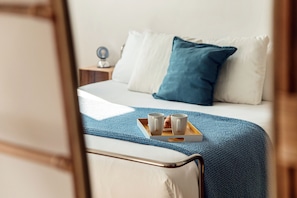 A neatly made bed with a blue blanket, two white pillows, and a tray with two cups and a small plate. - Como in the Sky (Como)