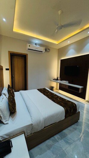 Quarto de hotel moderno com uma cama grande, televisão de tela plana na parede e aparelho de ar condicionado.
