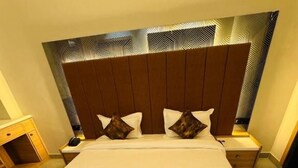 Habitación de hotel con una cama grande, un cabecero de diseño geométrico y una mesita de noche con lámpara.