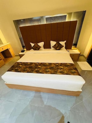 Habitación de hotel con una cama grande, un cabecero de diseño geométrico y una mesita de noche con lámpara.