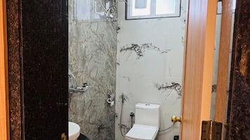Une salle de bain comprenant des toilettes, un lavabo et un espace douche.