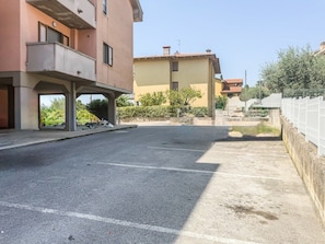 Ein Parkplatz mit einem Gebäude links und einem Zaun rechts.