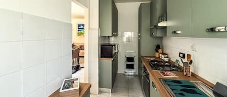A narrow kitchen with a central island, a built-in oven, and a stove.
