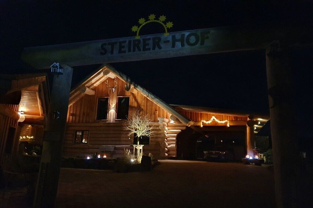 Een hotel in een blokhut met een bordje dat 'STEIERER-HOF' zegt bij de ingang.