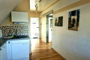 A kitchen with a tiled backsplash, a white cabinet, and a countertop with a sink. There are two framed pictures on the wall. - Holiday apartment with 2 bedrooms (Hessisch Lichtenau)