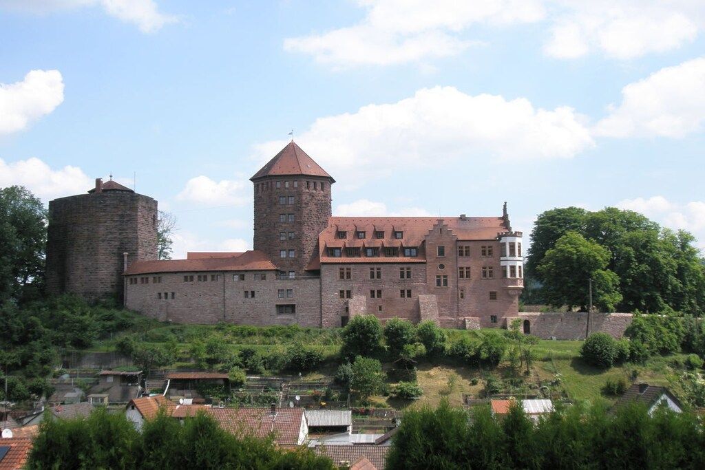A historic building with a prominent tower, a large courtyard, and a mix of stone and brick construction.