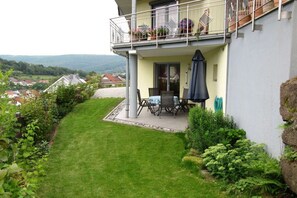 Un bâtiment à deux étages doté d’un balcon, d’une terrasse avec une table et des chaises, et offrant une vue sur le paysage environnant.
