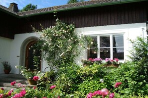 A white building with a brown roof, a window with a white frame, and a door with a wooden arch. - Apartment in Lindau with swimming pool (Lindau)