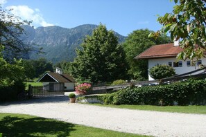 A rural property with a gravel driveway, a wooden fence, and a mountain backdrop. - Holiday apartment with 1 bedroom (Bayerisch Gmain)