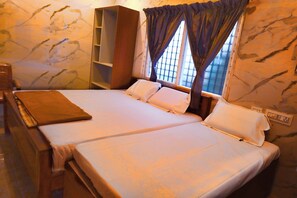 A hotel room with two beds, a wooden wardrobe, and a window with curtains. - Maruti residency (Tiruvannamalai)